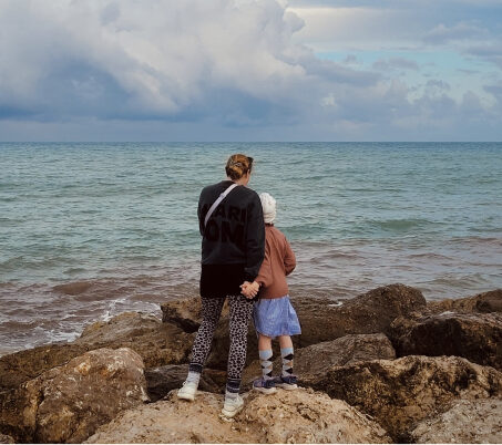 Mutter steht mit ihrer Tochter am Meeresufer