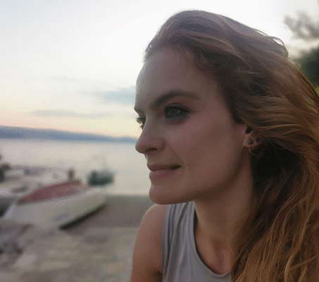 Patientin mit langen Haaren sitzt im Profil an einem See bei Sonnenuntergang und blickt entspannt zur Seite